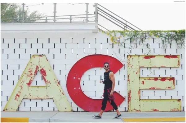 Colin má na sebe košeľu GoodhYOUman, náramok Lokai, flanelovú košeľu Ben Sherman, džínsy AG Jeans a slnečné okuliare Garrett Leight.