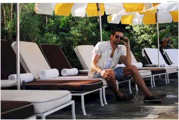 Colin má na sebe náhrdelník Kyle Chan, tielko GoodhYOUman, gombíkový Kennington, šortky Big Star a slnečné okuliare Barton Perreira.