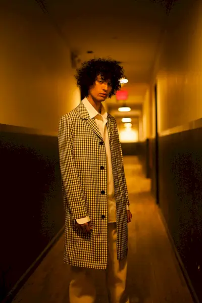 Liam veste casaco AMI, camisa Gosha Rubchinskiy, calça Carhartt e sapato Converse.