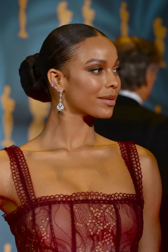 Elegantný nízky drdol s deleným stredom a lesklým povrchom ideálny na udalosti s čiernymi kravatami a glam na červenom koberci' title=