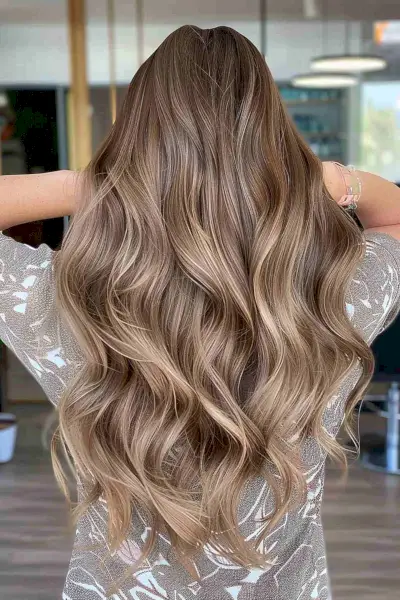 Long wavy light brown hair with tan undertones and subtle balayage highlights
