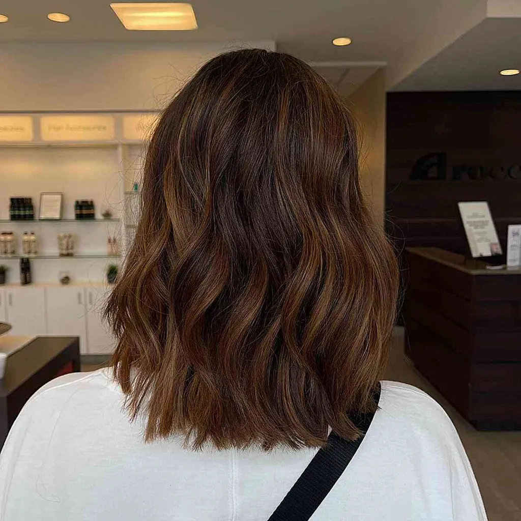 לאטה בראון עם הדגשות קרמל על שיער גלי בינוני' title=