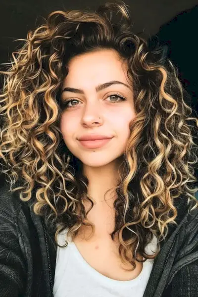 Medově blond odlesky na tmavých espresso hnědých dlouhých kudrnatých vlasech.