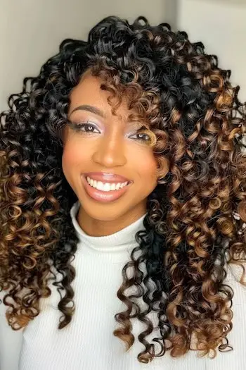 Karamelhøjdepunkter på krøllet mørkebrunt sort hår.