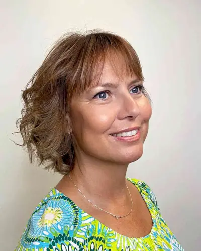 Light Cinnamon Hair Color for Mature Women Passed 60 with Curled Bob and Bangs