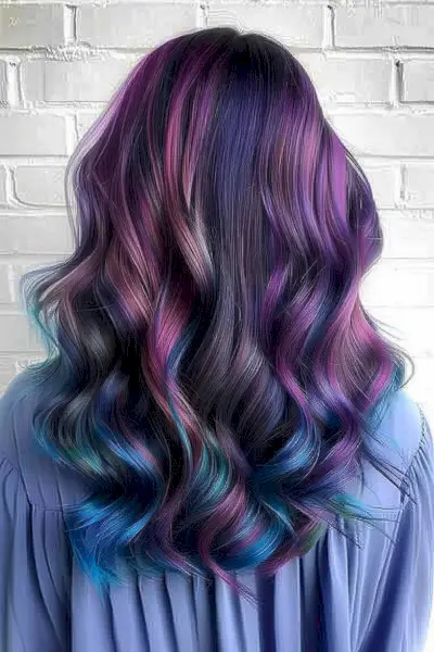 Long wavy hair transitioning from dark roots through silver to metallic light brown lowlights