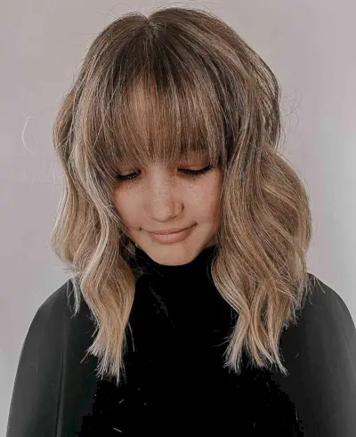 Soft Balayage Blonde Hues on Shoulder-Length Medium Brown Hair with Bangs