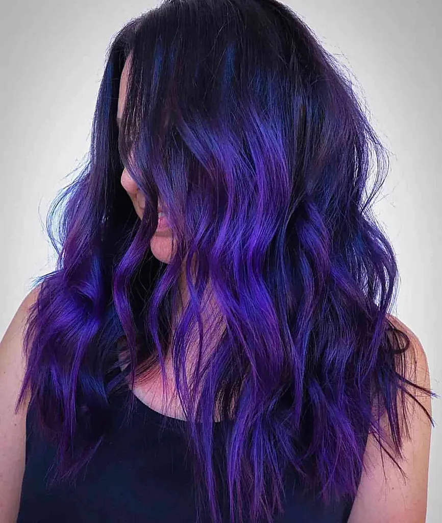 Violet profond électrique avec teinte bleue sur cheveux mi-longs avec vagues et dimension' title=