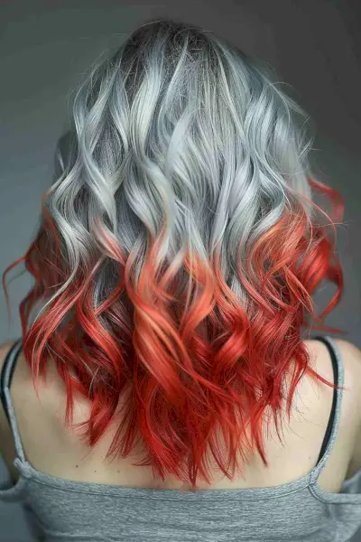 Medium-length wavy hair with a vivid silver to red ombre effect