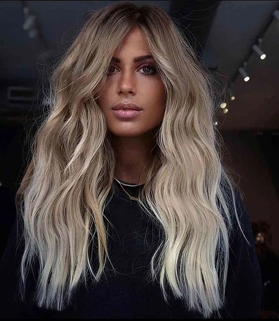 Geschmolzenes, butterartiges Platinblond mit helleren Enden und dunkleren Wurzeln für welliges Haar' title=