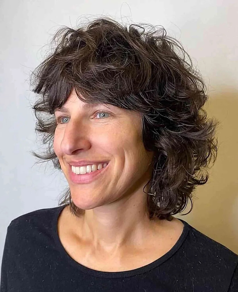 Pierzasty, kręcony krój sięgający ramion z frędzlami na noc dyskotekową' title=