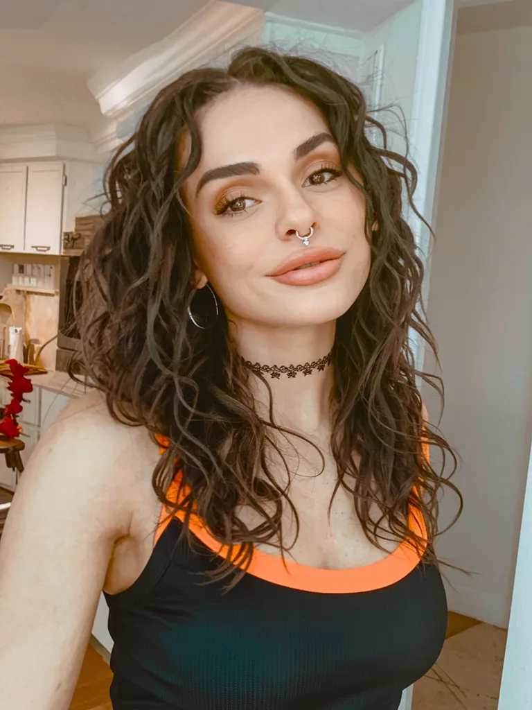 תספורת אימו מתולתלת באורך בינוני עם שכבות רכות ונפח טבעי' title=