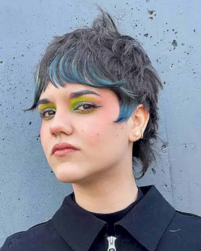 Shaggy mullet with choppy layers and teal highlights on thick, wavy hair