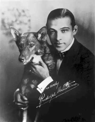 Îmbrăcându-și părul pe spate, actorul italian Rudolph Valentino pozează pentru un portret cu câinele său.