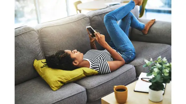 woman lying on couch looking at phone