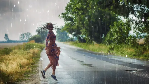 Woman dancing in the rain on a rural road