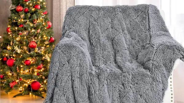 Shaggy gray blanket on a white chair in front of a Christmas tree