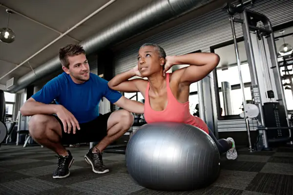 personal trainer helping woman