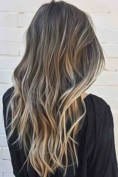 Long layered V-cut hairstyle with natural-looking beach waves and blonde gradient