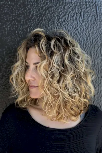 Medium-length layered curly bob with balayage highlights
