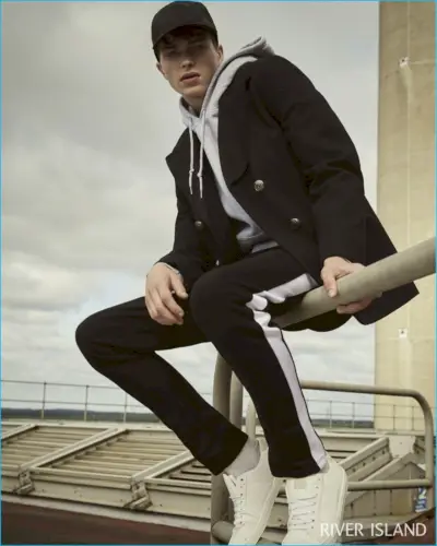 Aducând un aspect casual unui palton elegant bleumarin, Jake Love poartă un hanorac River Island în culoarea gri.