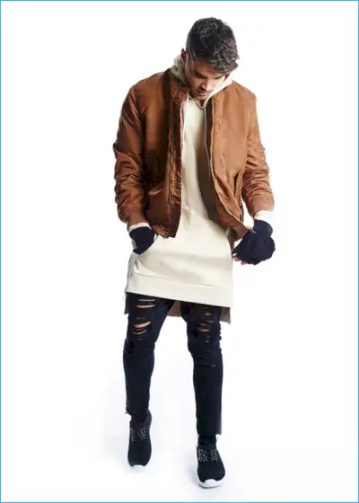 Josh Cuthbert na sliki v bombažni jakni, strganih kavbojkah iz jeansa in dolgi majici s kapuco znamke BoohooMAN