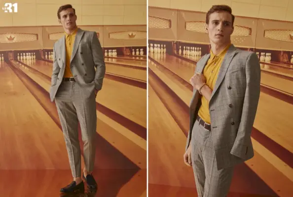 Julian Schneyder enfile une veste croisée Prince de Galles caramel LE 31 et un pantalon de costume avec un polo en maille soyeuse jaune foncé.