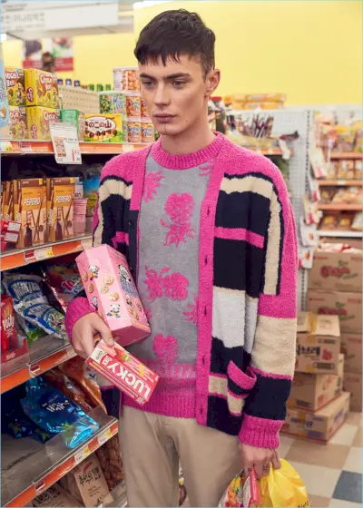 Simon Kotyk giver et statement i pink og bærer en Sacai-stribet cardigan og ananasstrikket pullover. Simon omfavner det basale til resten af ​​sit look og ifører sig Acne Studios satinbukser.