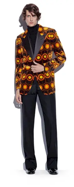 マーク・アンドレ・タージョンは、グラフィックプリントのカクテルジャケットにカシミアのタートルネックセーター、サテントリムのイブニングパンツ、トムフォードのレザードレスシューズを合わせています。
