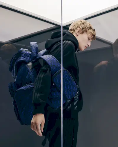 Nikita Stsjolokov v športnem zimskem videzu navdušuje s kapuco iz bombažnega džersija s tremi črtami Moncler x adidas Originals in najlonskim nahrbtnikom z logotipom.