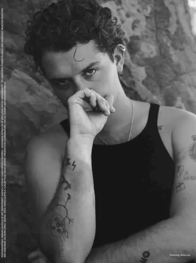 熱心で内省的なラフ・ローは、タトゥーが全面に表示された状態で、カメラのレンズを通して見つめています。