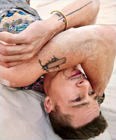 Brad Pitt legger seg ned og har på seg en Missoni-genservest med Giorgio Armani-bukser, en Tudor-klokke og et Miansai-armbånd.