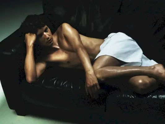 革張りのソファでリラックスするトロイ・シヴァンは、VMAN でプラダを着ています。