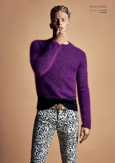 Clark Bockelman valt op in een getailleerde trui met ronde hals en een broek met print van Coach, met een Versace-riem.