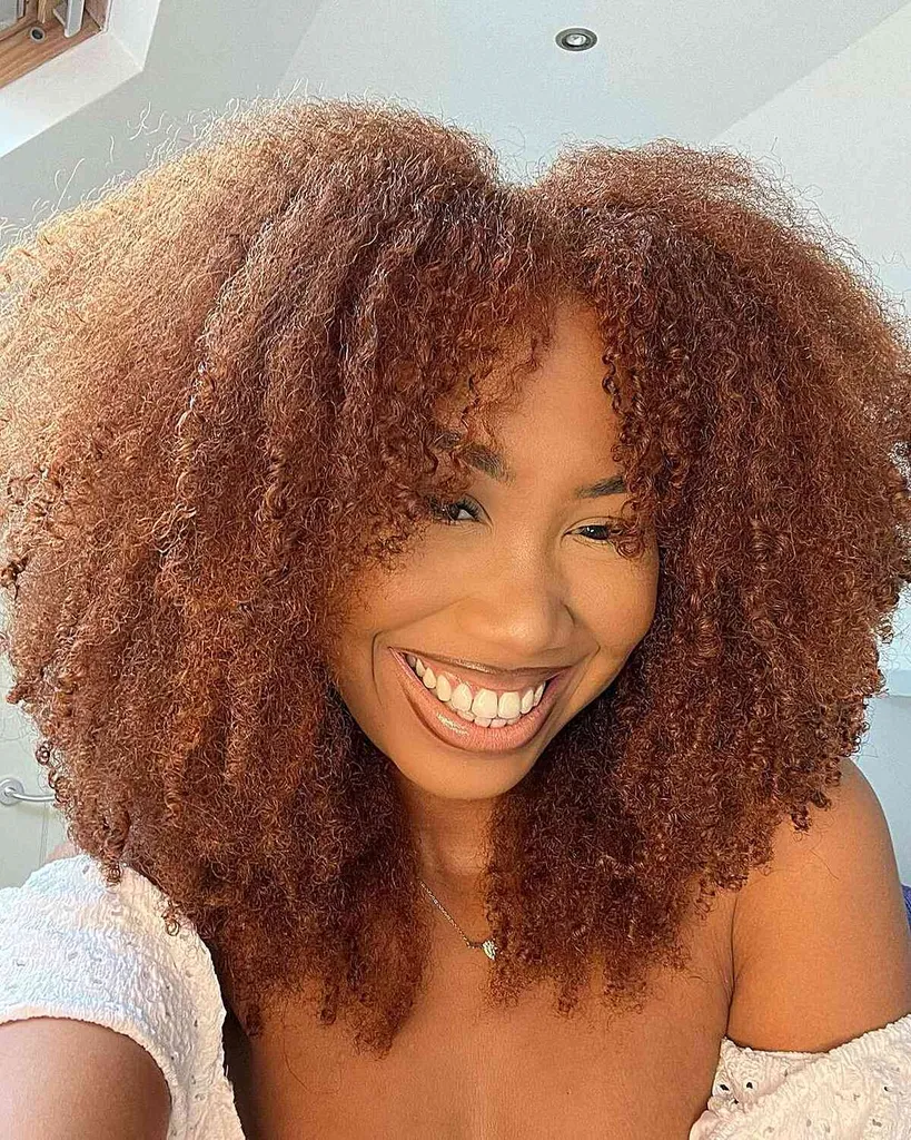 Pluizige gelaagde medium snit met natuurlijke dikke krullen en gezichtsomkaderende pony' title=