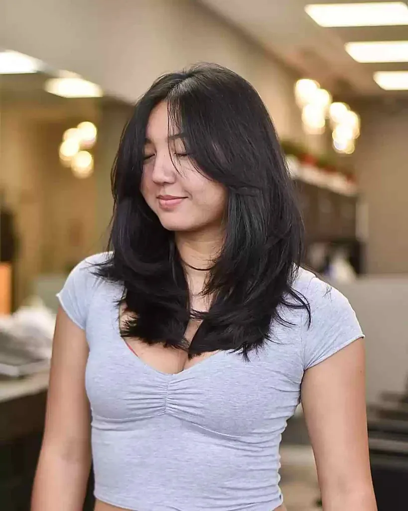 Rechte gelaagde snit met gezichtsomkaderende pony en middenscheiding op dicht haar' title=