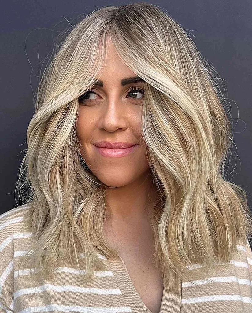 Prachtig blond verijdeld dik middellang haar voor dames met stompe uiteinden en middenscheiding' title=