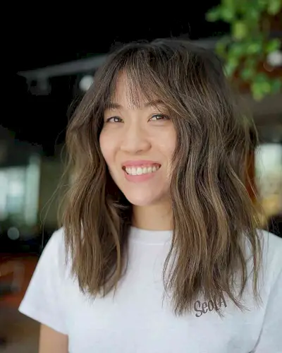 Versatile Brunette Mid-Length Chop with wispy bangs and textured layers