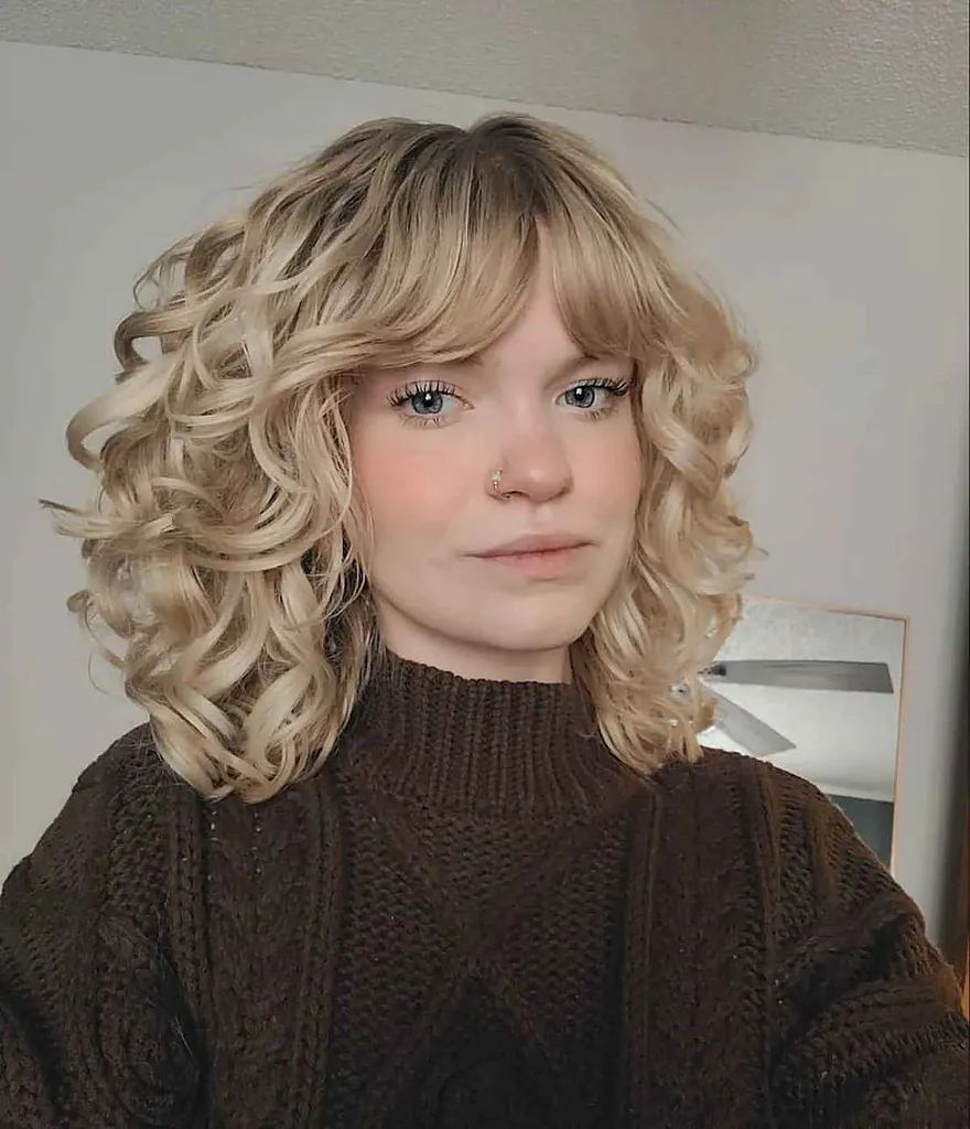 Capelli ricci lunghi fino alla clavicola con frangia' title=