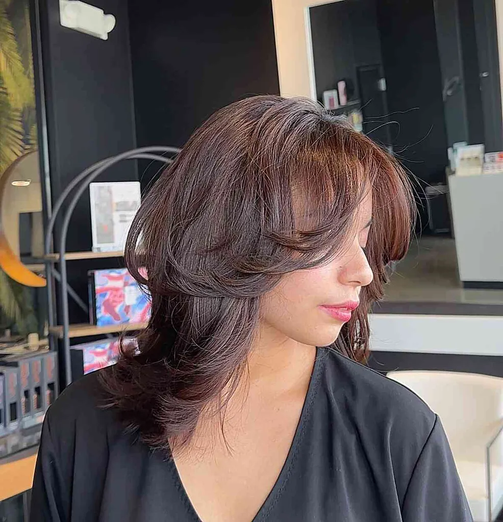 Stredne dlhý perový strih s vrstvenou ofinou rámujúcou tvár' title=