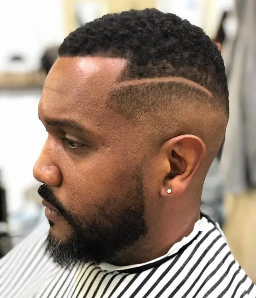 Corte Buzz con line up y mid fade con raya en el cabello.' title=