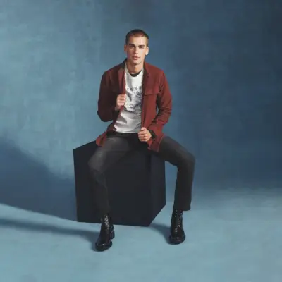 Auf dem Weg ins Fotostudio rockt Jake Hart ein Langarmshirt mit einem grafischen T-Shirt und Jeans von Buffalo David Bitton.