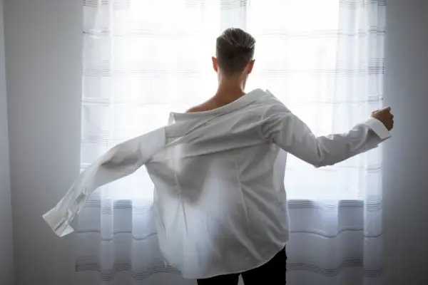 Man som sätter på sig en skjorta