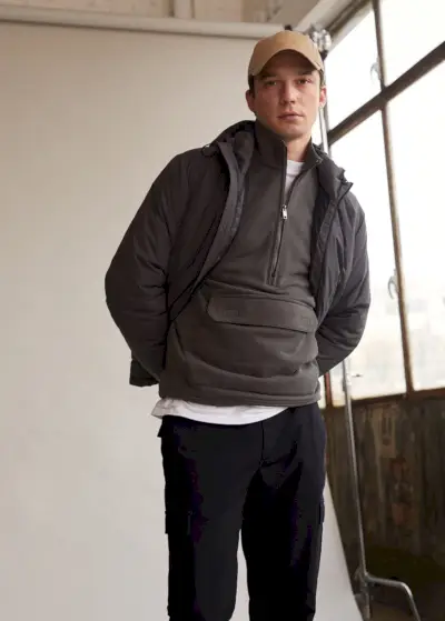 Für einen kühlen Tag trägt Alexis Petit einen Pullover mit halbem Reißverschluss, eine Jacke und eine Cargohose von Mango Man.