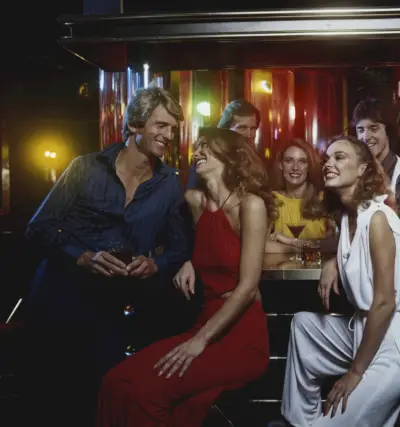 Uživa v noči v diskoteki, moški nosi delno odpeto svileno srajco.