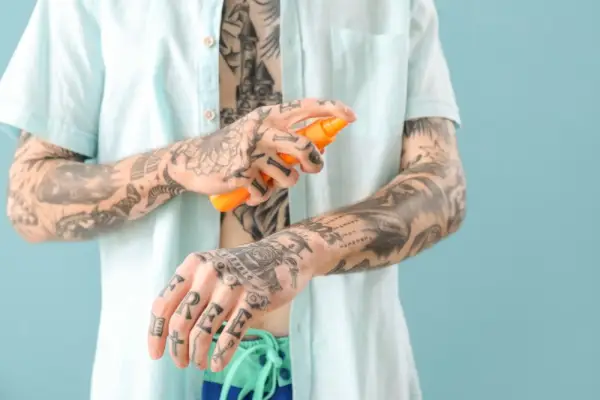 Man med tatueringar Solskyddskräm närbild