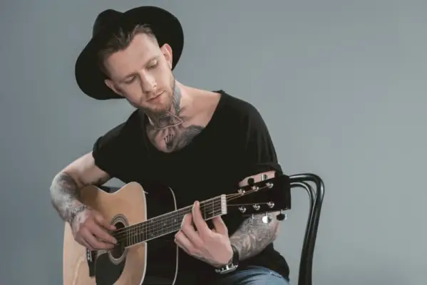 Man tatueringar spelar gitarr