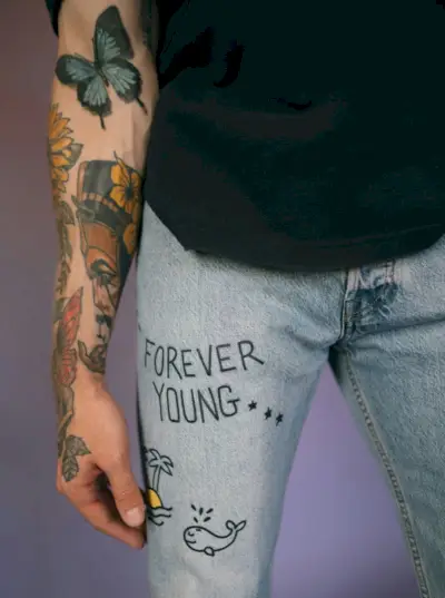 En livlig sommerfugletatovering flagrer på underarmen og symboliserer transformation og skønhedens flygtige natur.