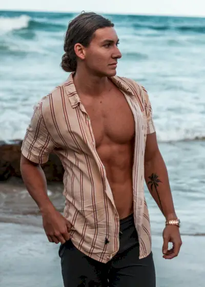 En ensom palmetatovering står på underarmen, et symbol på tropisk ro og vedvarende modstandskraft.