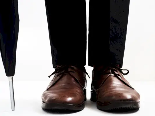 Braune Schuhe mit einer schwarzen Hose oder einem Anzug sind ein zeitgemäßer Stiltrend.